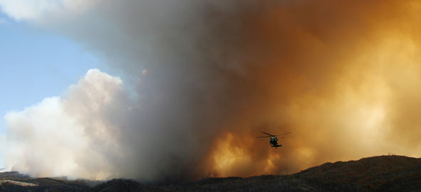 Helicopter above wildfire smoke cloud