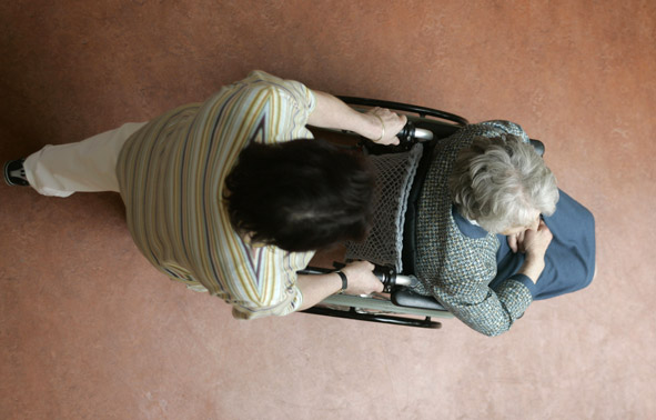Elderly woman in wheelchair being pushed by a man.