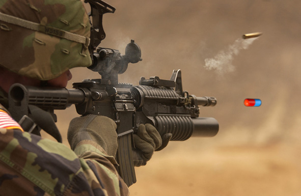 Solider firing rifle with a pill emerging from barrel