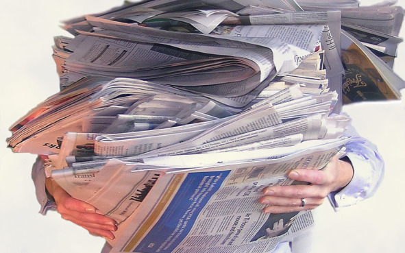 person holding stack of newspapers