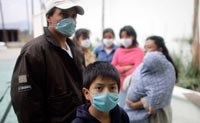 People wearing face masks stand near the home of Gerardo Leyva, one of the first victims of swine flu, in the town of Xonacatlan, Mexico