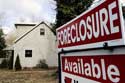 for sale sign that read Foreclosure in front of a tan house