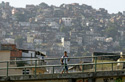 A student crosses a bridge to arrive to his school, on the background is seen the Rocinha slum in Rio de Janeiro, Brazil